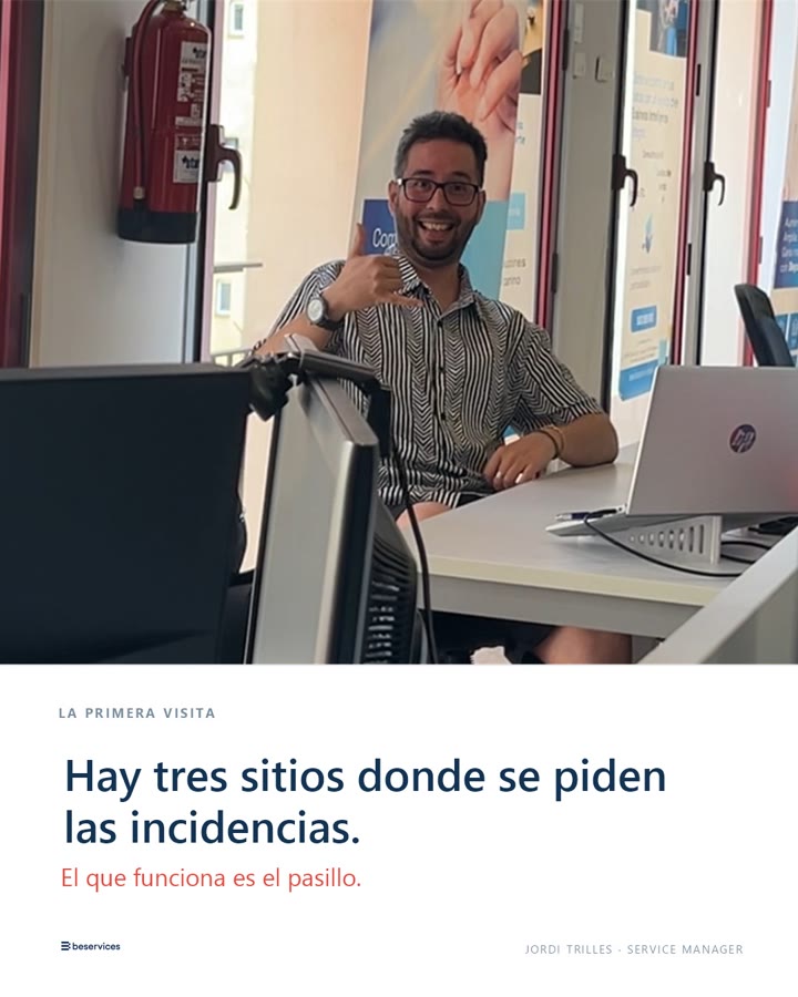Jordi Trilles, sentado a un escritorio con dos monitores y un extintor de fondo, sonríe haciendo un gesto de llamada con la mano. Rótulo: «Hay tres sitios donde se piden las incidencias. El que funciona es el pasillo.» Firma al pie: Jordi Trilles · Service Manager.